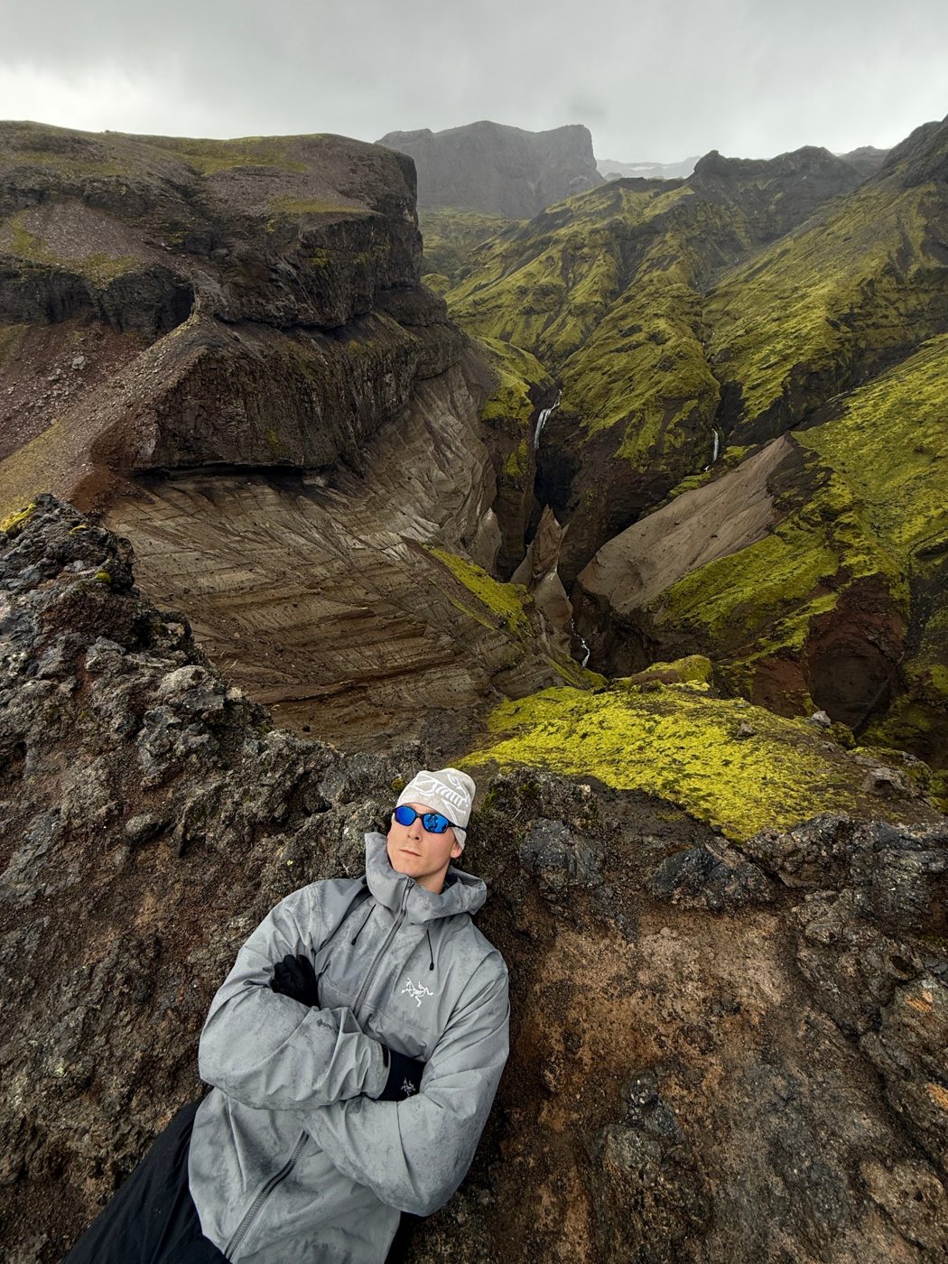 Ethan resting on a cliff edge above a mossy canyon in Iceland